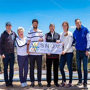 Four men and two women posing for a photo while holding a Snow Museum sign