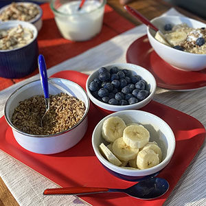 red white and blue colored bowls and flatware with oats, blueberries and sliced bananas